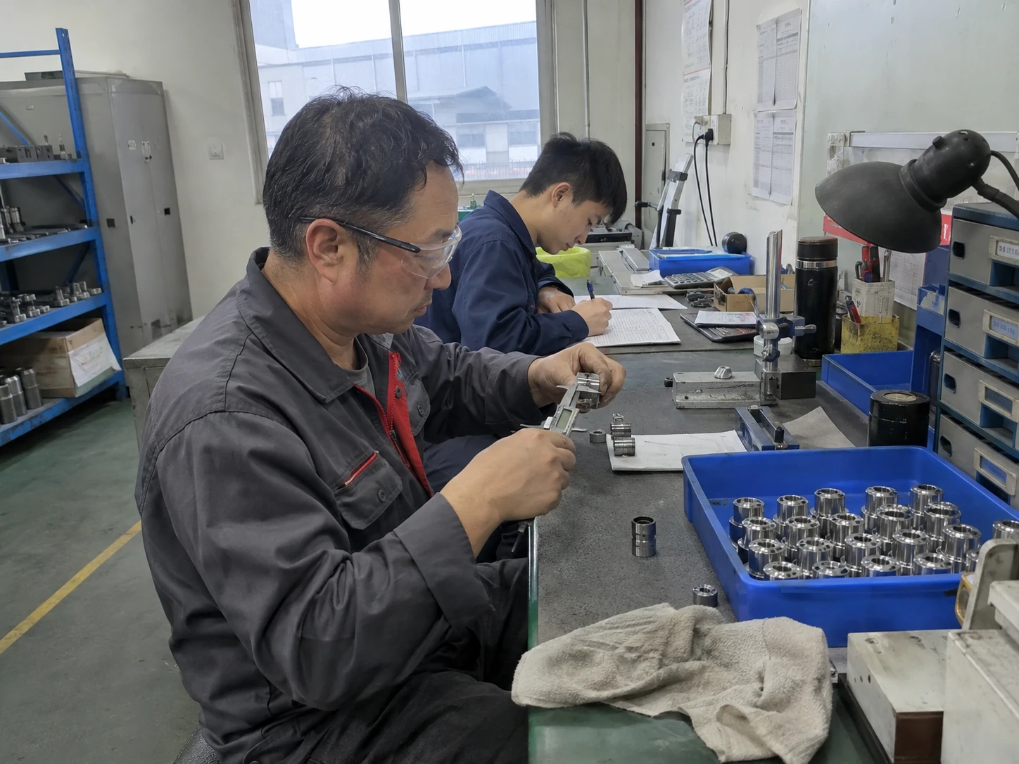 技术人员在工作台上测量零件并记录检查结果