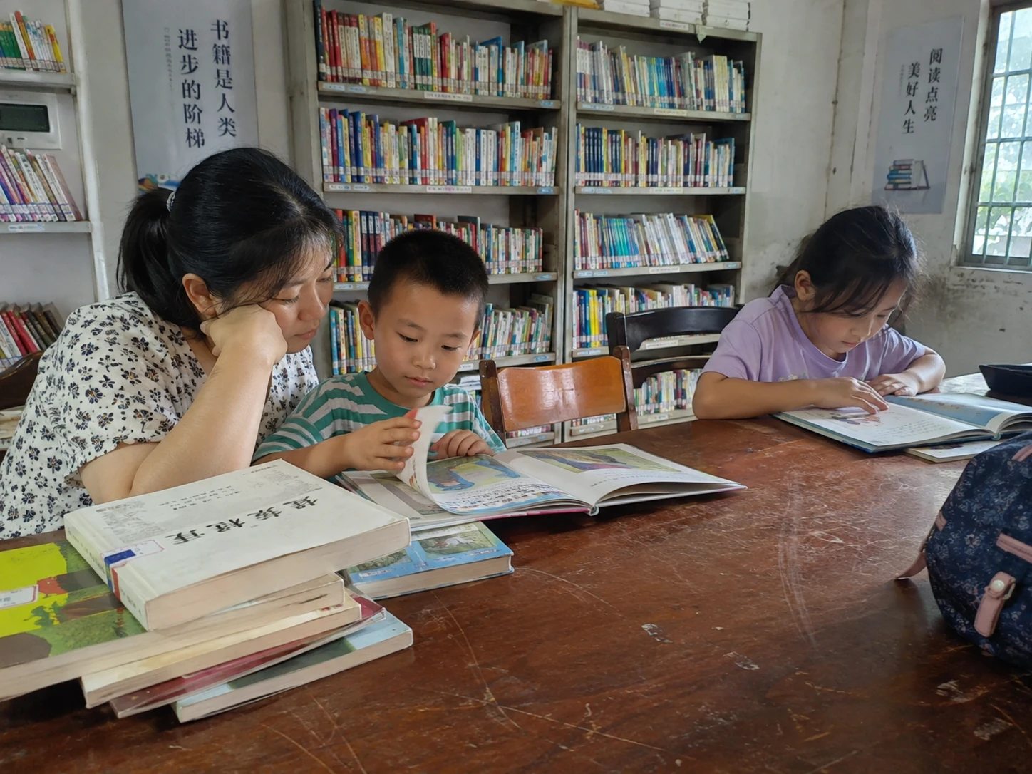 社区阅读桌旁,大人与孩子翻阅图画书并交流